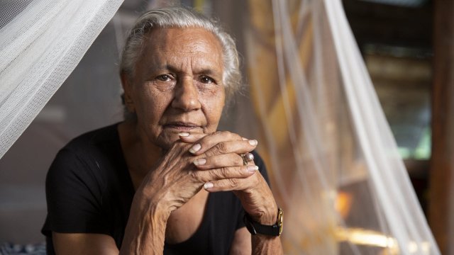 Photograph of Aboriginal media pioneer Freda Glynn, who gazes at the camera, her fingers interlocked.